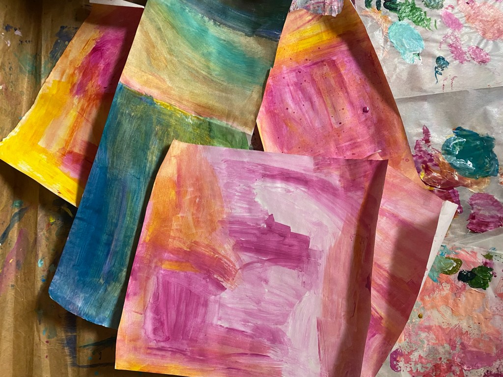 sheets of poster paper painted with pink, yellow and green acrylic paint