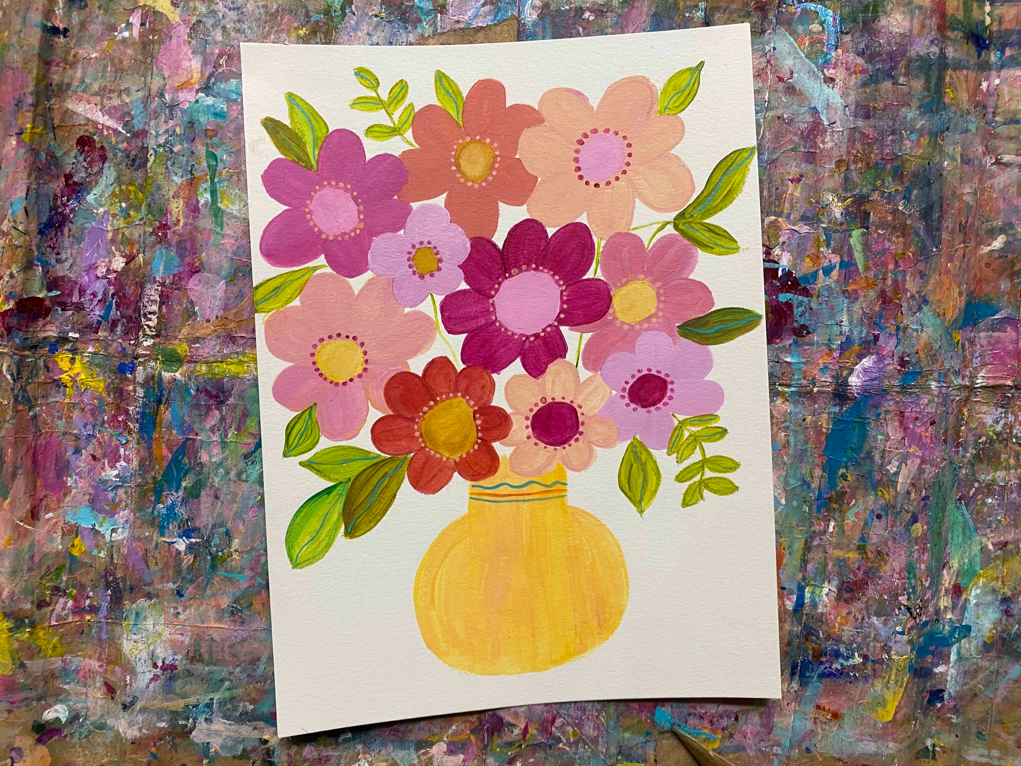 a yellow vase filled with orange and pink abstract daisies