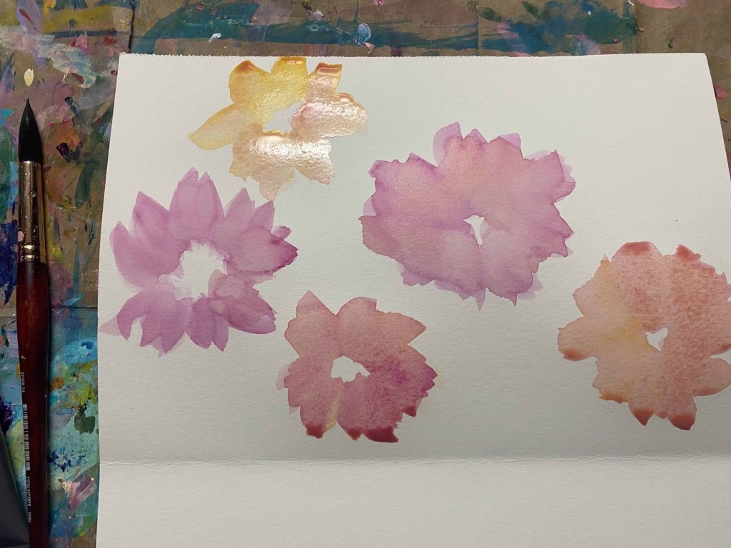 using a big brush and watercolor to paint abstract flowers